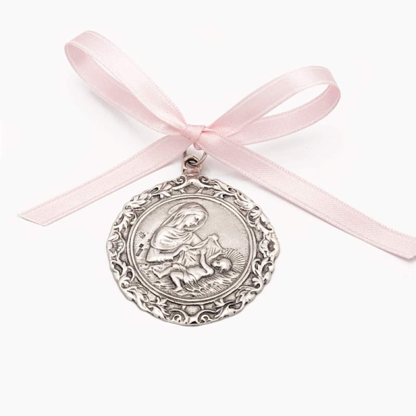 Medalla de cuna realizada en plata de ley con la imagen de la Virgen y el Niño en Belén, con cerco repujado.
Reverso en liso ide