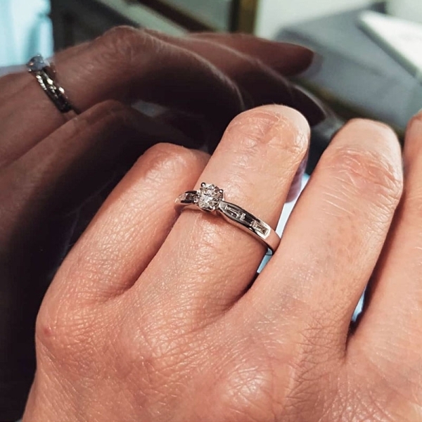 Solitario realizado en oro blanco de primera ley con un diamante talla brillante central y varios diamantes en talla baguette en