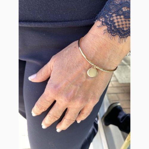 Pulsera rígida lisa con chapita colgando, con un cómodo cierre que se mete por el tubo, realizada en oro amarillo de primera ley