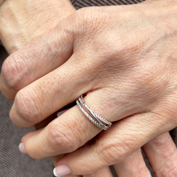 Sortija cruzada con una banda lisa y otras dos con diamantes en talla brillante. En oro blanco de 18 ct