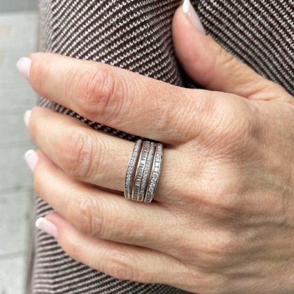 Sortija ancha con cuatro bandas engastadas con diamantes en talla brillante y baguette. En oro blanco de 18 ct