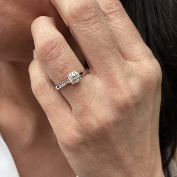 Solitario rosetón con un diamante central rodeado de diamantes más pequeños. En oro blanco de 18 ct