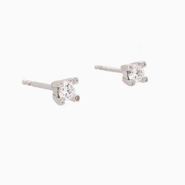 Pendientes de cuatro patas con un diamante central y un diamante en cada pata, realizados en oro blanco de primera ley. Cierre d