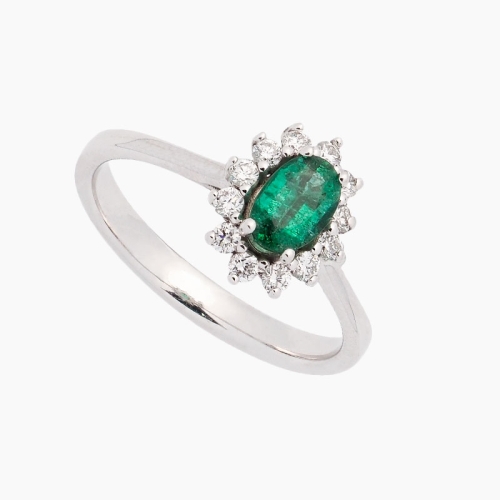 Sortija de estilo clásico con una esmeralda central en talla oval y orla de diamantes alrededor. Oro blanco de primera ley