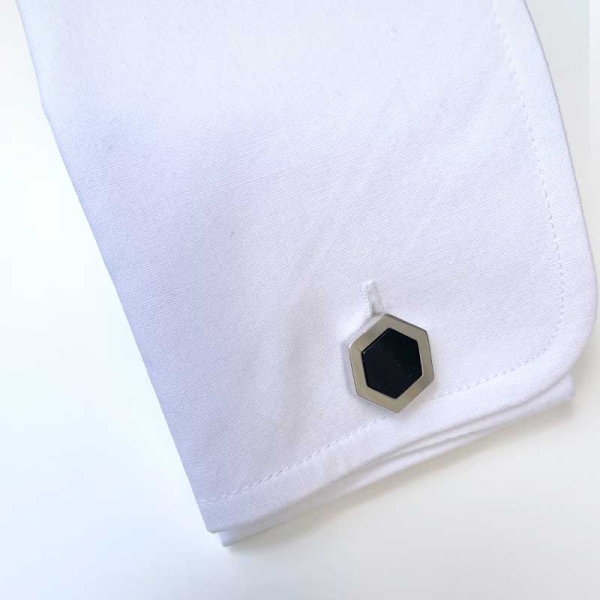 Gemelos con forma hexagonal y una piedra de ónix en el centro realizados en plata de ley y baño de rodio. Con pie plegable