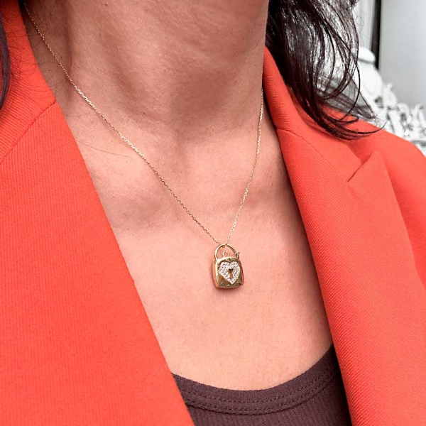 Colgante con forma de candado en oro amarillo de primera ley y un corazón en el centro engastado con circonitas.