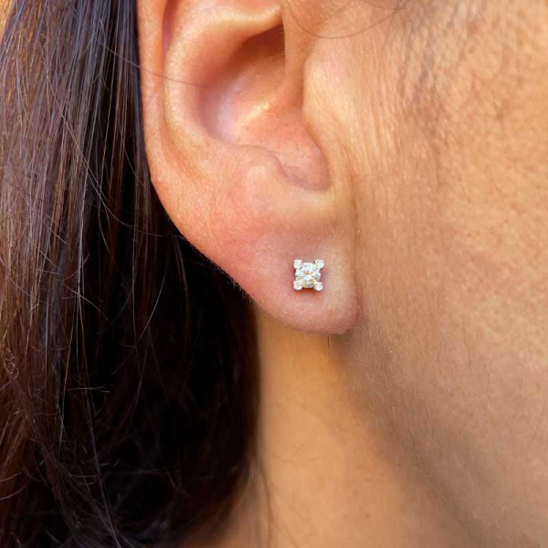 Pendientes de cuatro patas con un diamante central y un diamante en cada pata, realizados en oro blanco de primera ley. Cierre d
