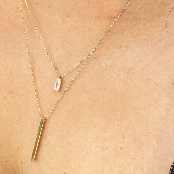 Gargantilla doble con una cadena más larga que otra y dos colgantes diferentes en circonita y oro amarillo de primera ley. Cierr